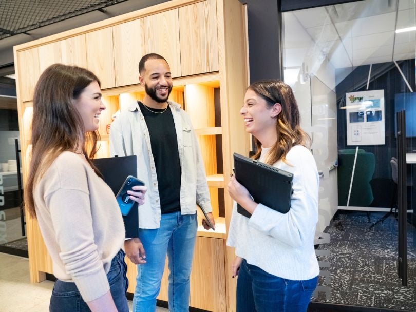 Three DraftKings team members chat together in a hallway in the company’s office